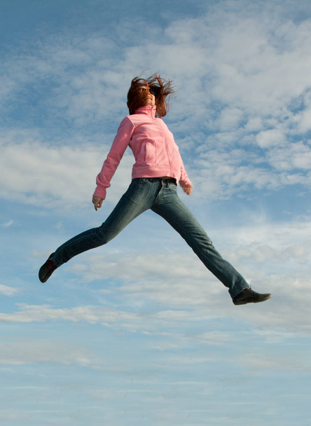 Girl in jump on background sky in red sweater - Zdjęcie, obraz