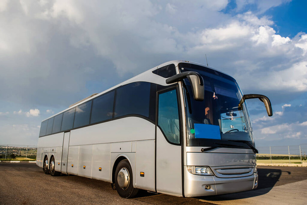 Autobús alojado en el aparcamiento bajo un cielo azul con nubes
 - Foto, imagen