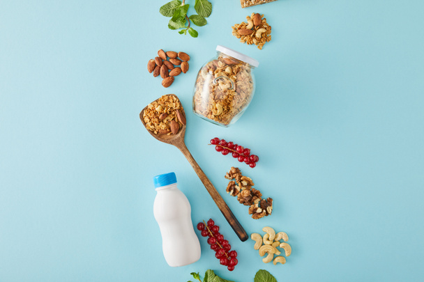 Vue du dessus de la composition alimentaire des noix, bouteille de yaourt, baies et feuilles de menthe sur fond bleu
 - Photo, image