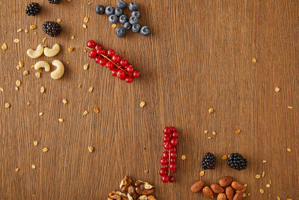 Yaban mersinleri, kırmızı üzümler, cevizler, bademler, ahşap arka planda kaju fıstıkları. - Fotoğraf, Görsel