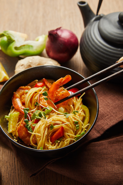 cropped view of woman eating noodles with shrimps and vegetables with chopsticks - Photo, Image