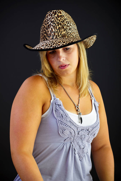 Young blond woman with hat on black background, studio shot. Adobe RGB - Zdjęcie, obraz