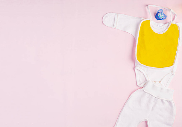 Vauvan vaatteita ja muuta tavaraa lapselle vaaleanpunaisella taustalla. Vastasyntyneen lapsen käsite. Yläkuva
 - Valokuva, kuva