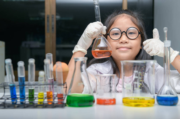 Щаслива маленька дівчинка в лабораторному пальто робить експеримент
  - Фото, зображення