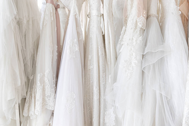 Beautiful, White bridal dress texture on background. Wedding dresses hanging on a hanger interior of bridal salon. Design, fashion modern luxury in detail. - Foto, immagini