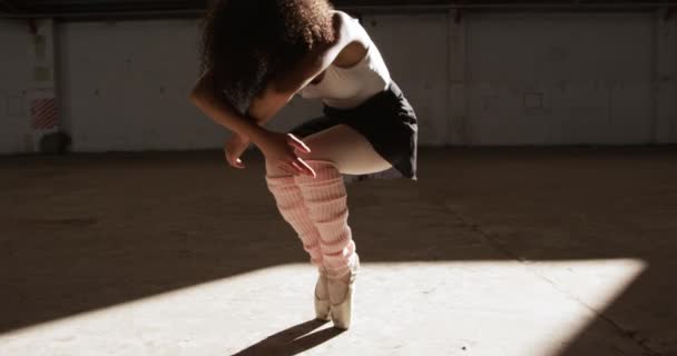 Low angle front view of a mixed race female ballet dancer practicing in an empty warehouse, standing up on tiptoes, slow motion - Filmmaterial, Video