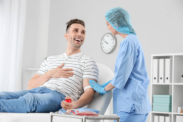 Doctora preparando donante masculino para transfusión de sangre en el hospital
 - Foto, Imagen