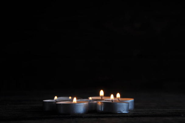 Запалені маленькі свічки, викладені поспіль на дерев'яному столі. Розмитість. Символ. Натюрморт
 - Фото, зображення