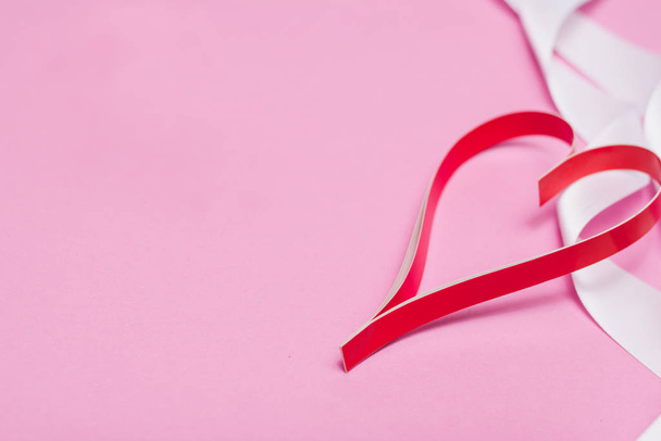 Κόκκινη χάρτινη καρδιά σε ροζ φόντο με λευκή κορδέλα με αντιγραφικό χώρο - Φωτογραφία, εικόνα
