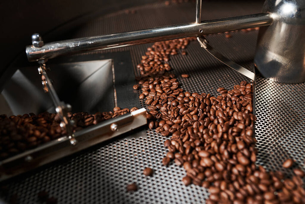 Koffie Roosteren Technologie. gebrande koffiebonen in een koffiebranderij. - Foto, afbeelding