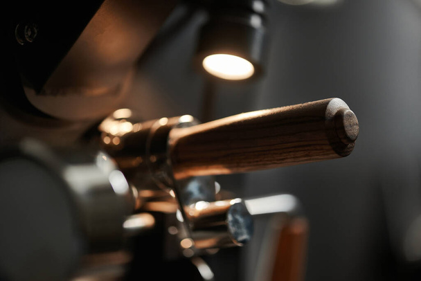 Szczegóły maszyny do pieczenia kawy z metalu i drewna za pomocą lampy. Zbliżenie. - Zdjęcie, obraz