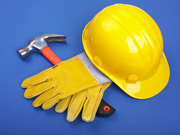 Worker equipment - HardHat Hammer And Leather Gloves on Blue - Фото, изображение