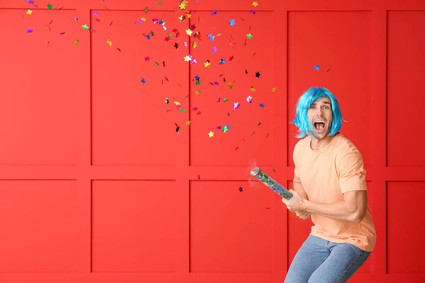 Man in funny disguise and with party noisemaker on color background. April fools' day celebration - Photo, Image