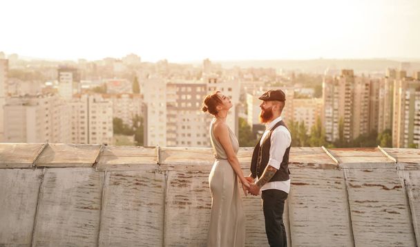 Stylish couple holding hands on roof - 写真・画像