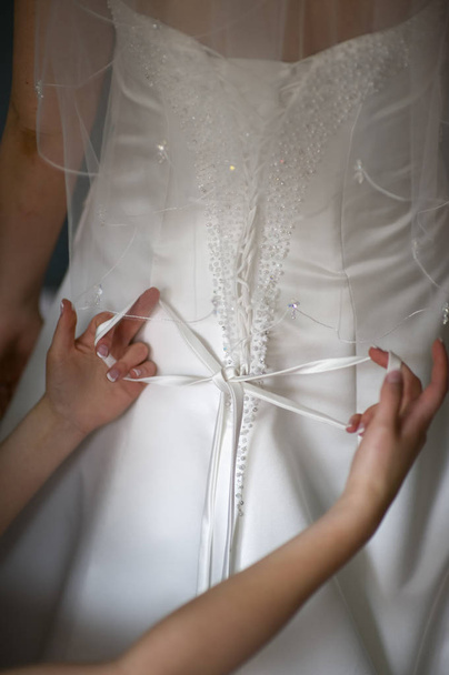 woman tying the bow on the wedding dress of a bride - Fotó, kép