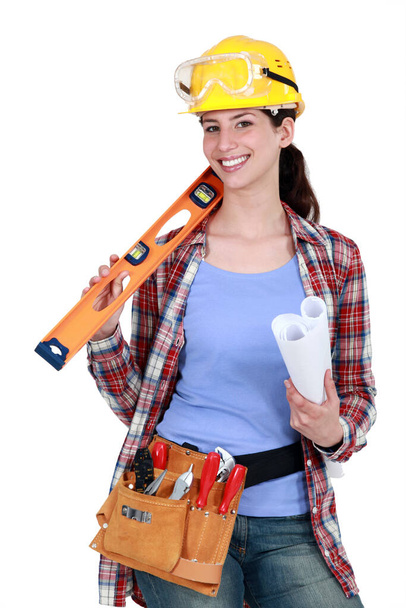 Female construction worker holding tools and a rolled-up plan - Fotografie, Obrázek