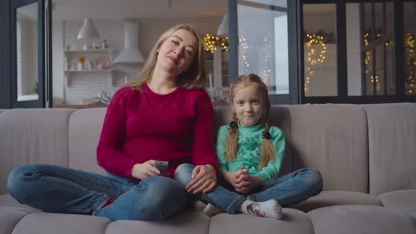 Mother and daughter watching tv on sofa at home - Séquence, vidéo