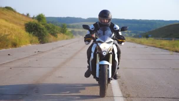 Homem de capacete dirigindo moto esporte poderoso na estrada com belo fundo. Motociclista excesso de velocidade na motocicleta com farol ao longo da estrada do país. Jovem a gostar de velocidade. Conceito de liberdade - Filmagem, Vídeo