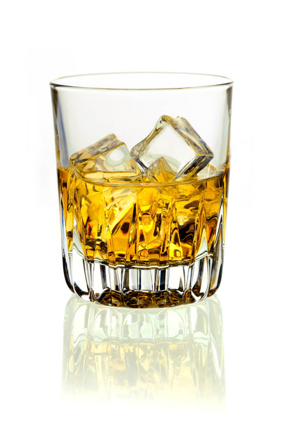 Closeup of a glass of golden whiskey on ice on a white background with reflection - Zdjęcie, obraz