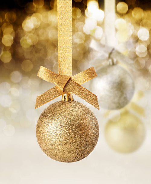 Hanging golden glitter textured Christmas ornament against a background of twinkling party lights - Foto, Imagem