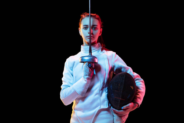 Teen girl in fencing costume with sword in hand isolated on black background - Valokuva, kuva
