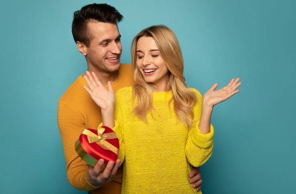 happy couple on studio background. man surprising woman with a gift   - Photo, image