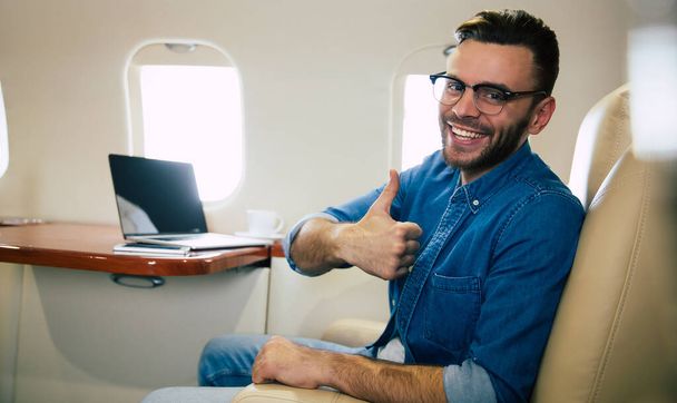 young businessman on the plane with thumb up - Φωτογραφία, εικόνα