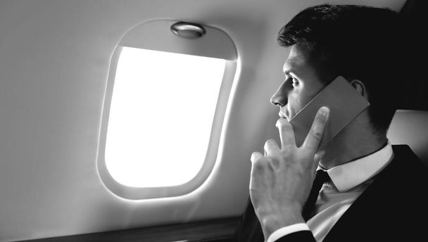 young businessman on the plane talking on smartphone  - Foto, imagen