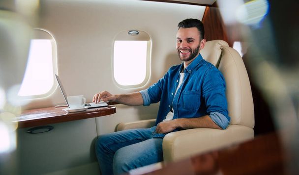 young businessman on the plane with laptop - 写真・画像
