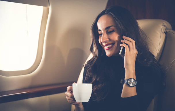 Young woman on plane talking on phone  - Fotó, kép