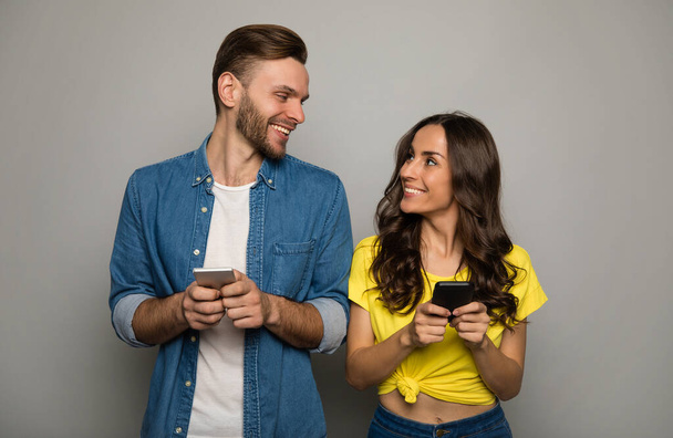 happy couple using smartphones on studio background  - Foto, Imagen