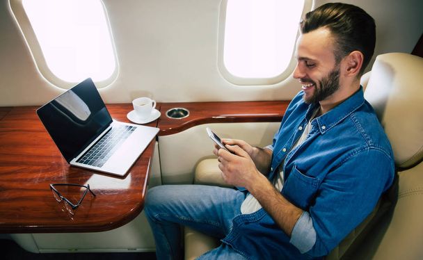 young businessman on the plane using smartphone  - 写真・画像