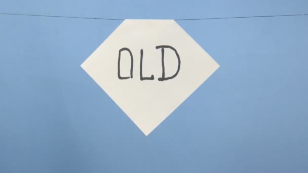Brandend en rokend wit velletje papier met een zwarte inscriptie "oud" op een blauwe achtergrond - Video