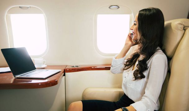 Young woman on plane using phone - Fotó, kép