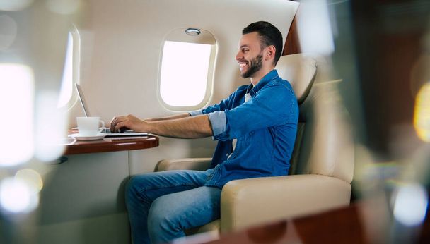 young businessman on the plane with laptop - Φωτογραφία, εικόνα