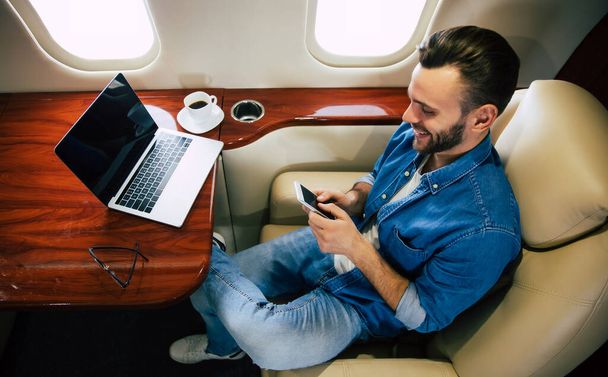 young businessman on the plane using smartphone  - 写真・画像