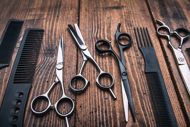 Stylish professional barber scissors on vintage wooden table, hairdresser salon concept, hairdressing tool set. Haircut accessories - Fotó, kép