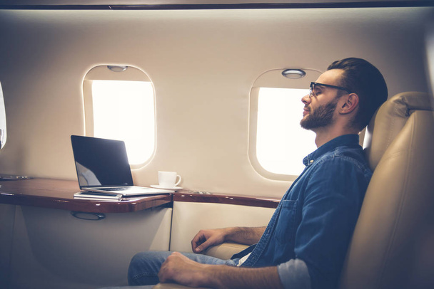 young businessman on the plane with laptop - Fotó, kép