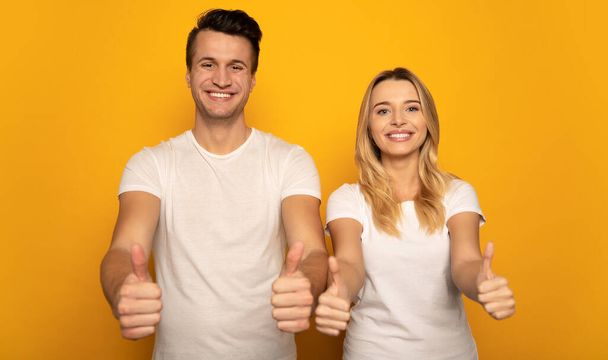 happy couple  with thumbs up on studio background  - Photo, Image