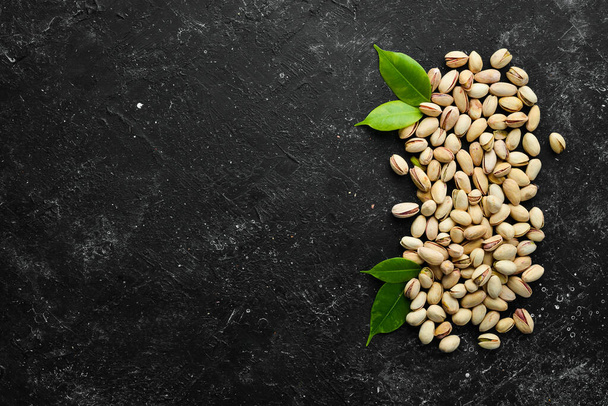 Salted pistachios on a black stone background. free space for your text. Top view. - Φωτογραφία, εικόνα