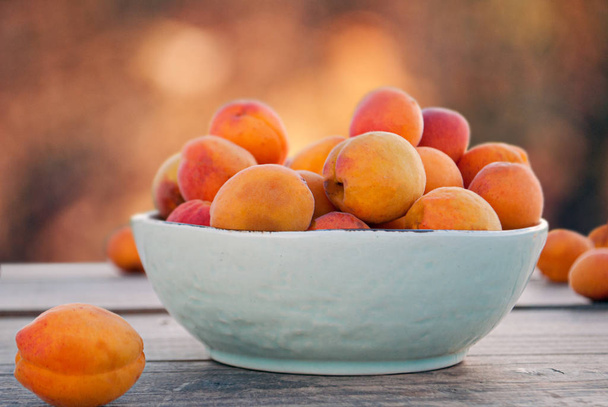 Apricots in a bowl and on a table - Photo, Image