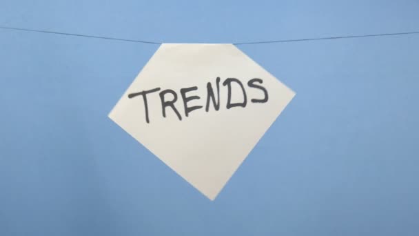 Hoja de papel blanco ardiente y humeante con una inscripción negra "tendencias" sobre un fondo azul
 - Metraje, vídeo
