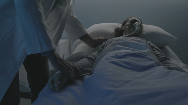 Γιατρός ελέγχει έναν ασθενή που βρίσκεται στο κρεβάτι στο νοσοκομείο - Πλάνα, βίντεο