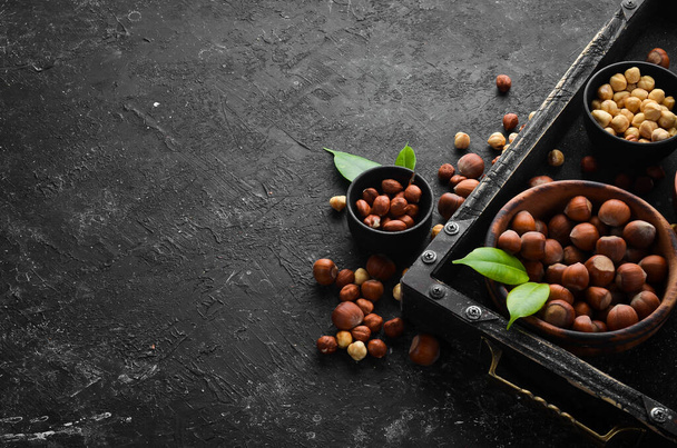 Hazelnuts in a bowl on a black stone background. Nut. free space for your text. Top view. - Фото, изображение