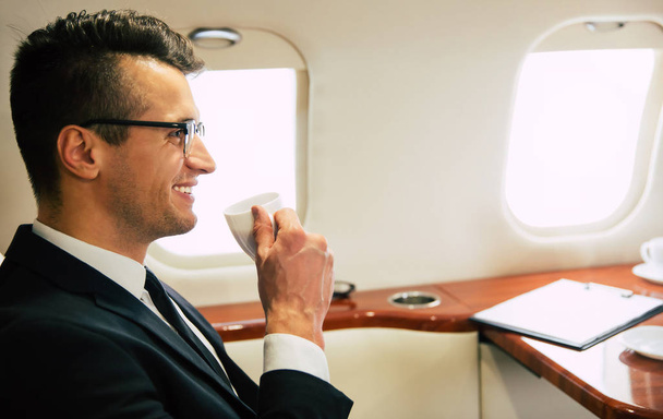 young businessman on the plane drinking tea  - Фото, зображення