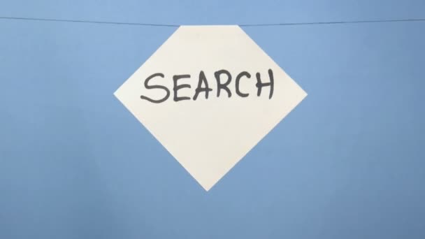 Κάψιμο και κάπνισμα λευκό φύλλο χαρτιού με μαύρη επιγραφή "αναζήτηση" σε μπλε φόντο - Πλάνα, βίντεο