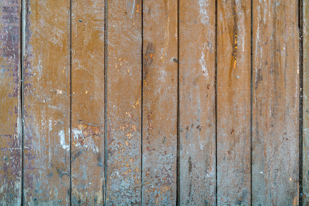 old painted wooden planks of yellow color are peeling off from time. Paint peeling off the wooden surface of the old planks. Texture of old painted wooden boards - Fotografie, Obrázek