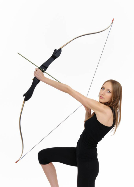 Beautiful kneeling woman aiming with bow and arrow - Fotó, kép