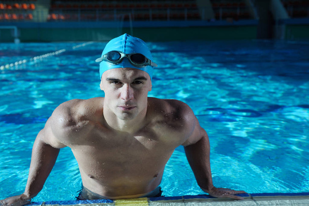 Happy muscular swimmer wearing glasses and cap at swimming pool and represent health and fit concept - Photo, Image