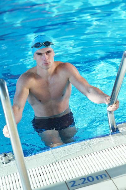 Happy muscular swimmer wearing glasses and cap at swimming pool and represent health and fit concept - 写真・画像